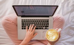 woman typing on laptop with coffee